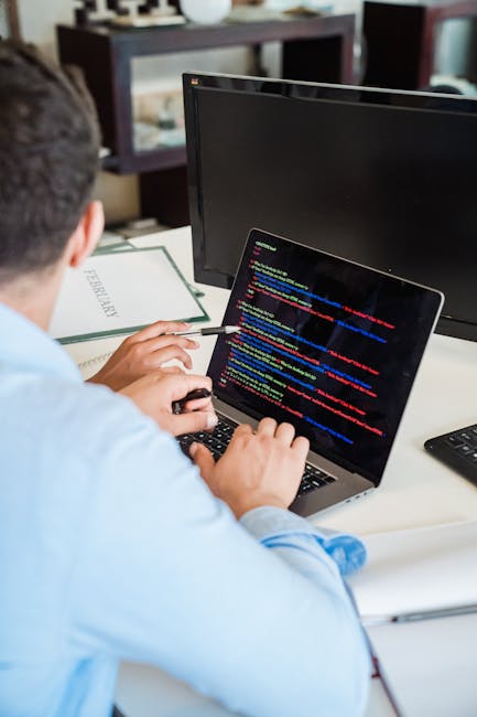 Photograph showing a close-up of a computer screen filled with lines of colorful programming code, including JavaScript and HTML syntax, with various keywords, functions, and variables visible in diff